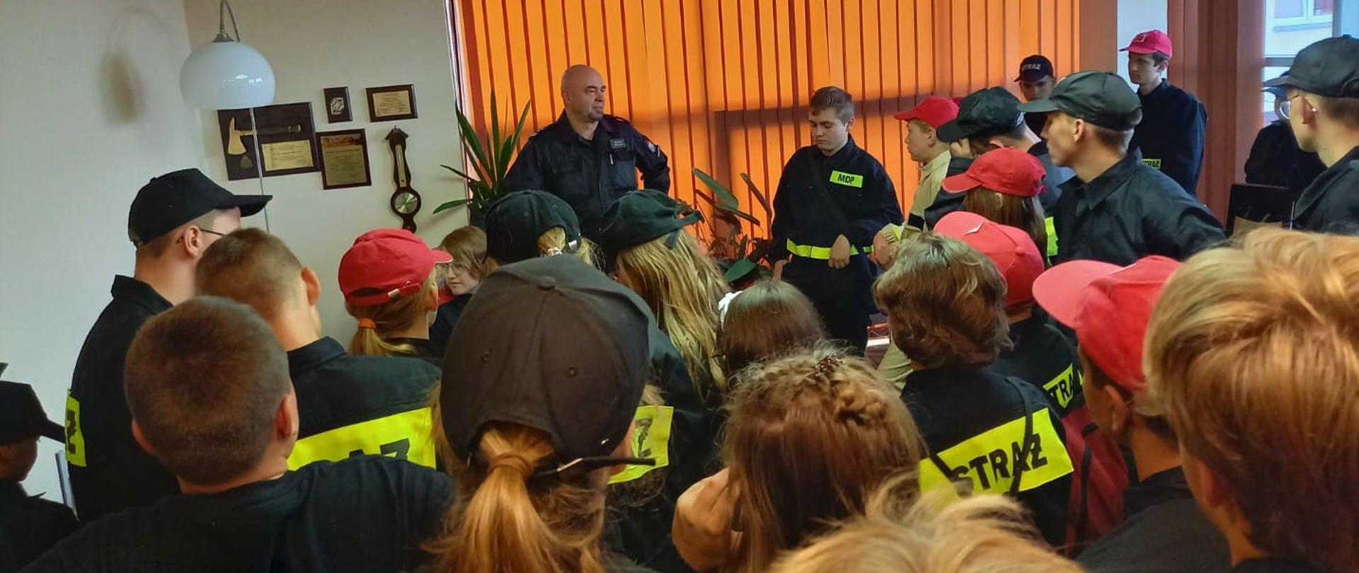 Zdjęcie przedstawia młodzież na wizycie u komendanta PSP