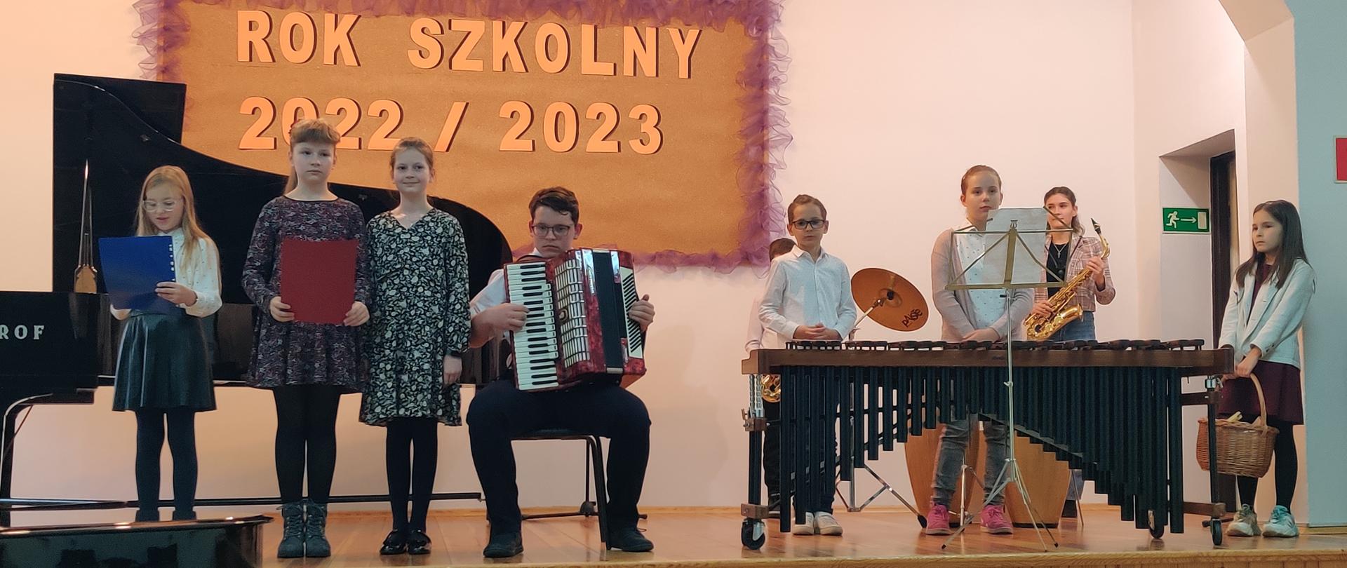 Zdjęcie grupowe przedstawiające wszystkich wykonawców podczas koncertu na scenie.