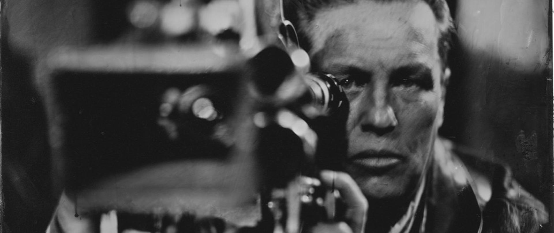 zdjęcie w kolorze czarno-białym przedstawia człowieka przy kamerze
