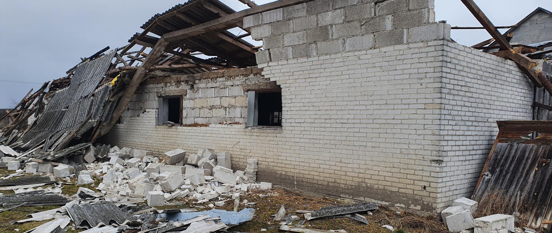 Zawalony dach w budynku gospodarczym. Leżące na ziemi części ścian i dachu budynku