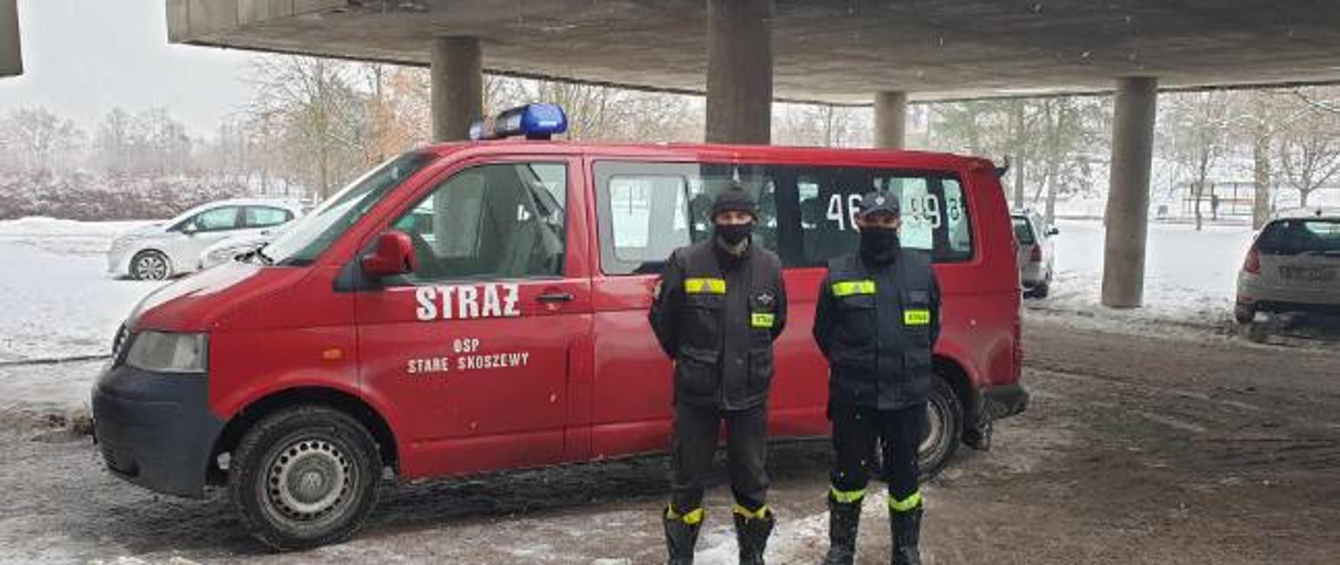 zdjęcie przedstawia dwóch ratowników OSP Stare Skoszewy na tle samochodu pożarniczego busa w kolorze czerwonym, pojazd oznakowany