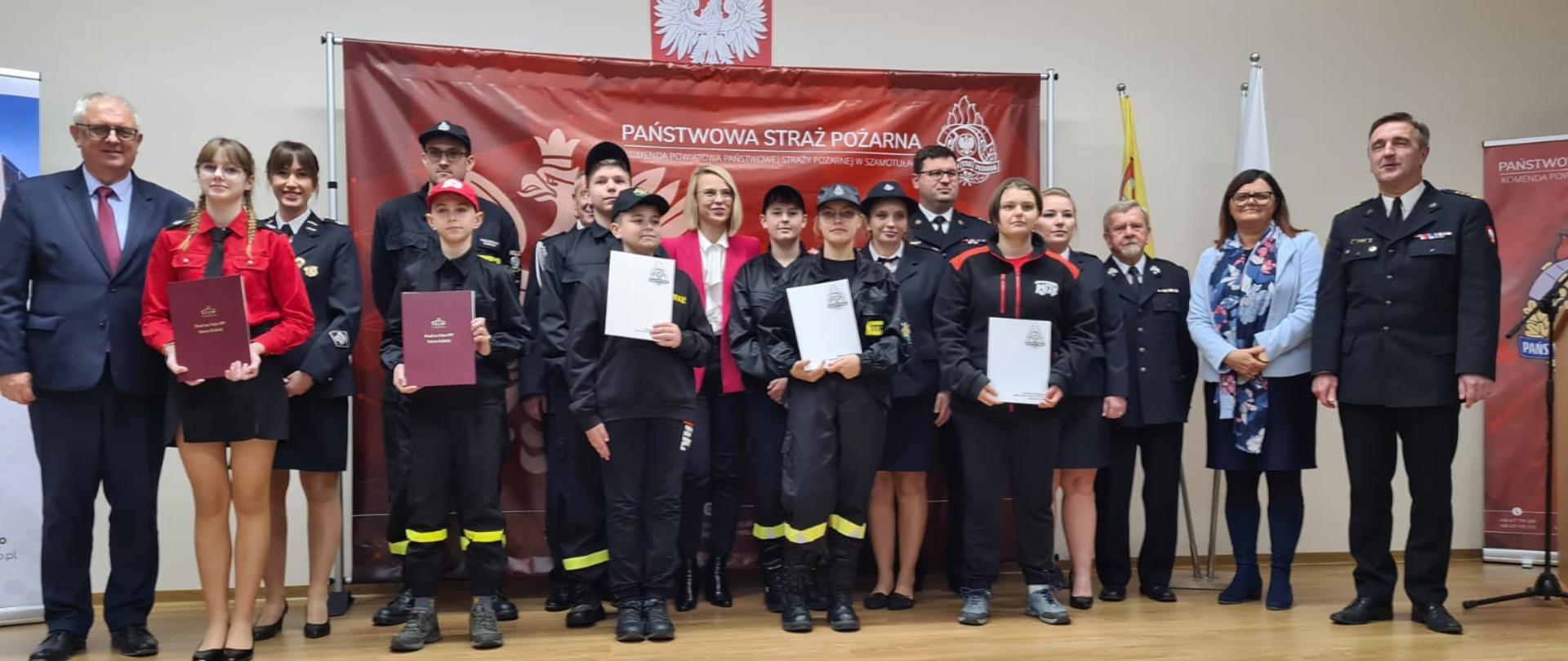 Po prawej Pan Grzegorz Piechowiak, w środku pani Marta Kubiak, obok zastępca Komendanta Wojewódzkiego w Poznaniu, strażacy MDP, po prawej Starosta Powiatu Szamotulskiego, Komendanta Powiatowy