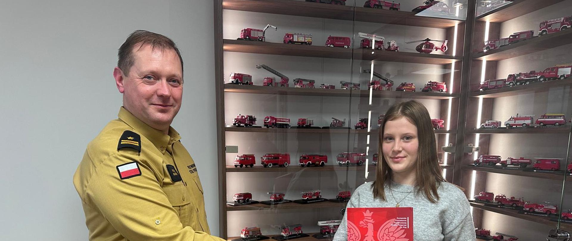 Na zdjęciu widać Komendanta Powiatowego PSP w Pile z Amelią, która udzieliła pomocy podczas wypadku. 