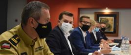 Małopolski Komendant Wojewódzki PSP melduje wojewodzie i premierowi o działaniach. Wszyscy siedzą przy stole