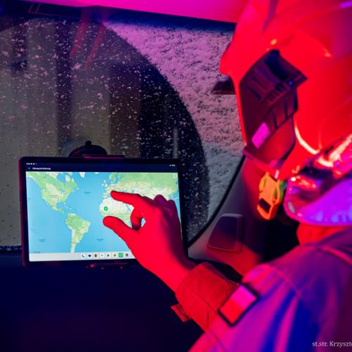 We wnętrzu wozu strażackiego strażak pracuje na tablecie zainstalowanym na desce rozdzielczej