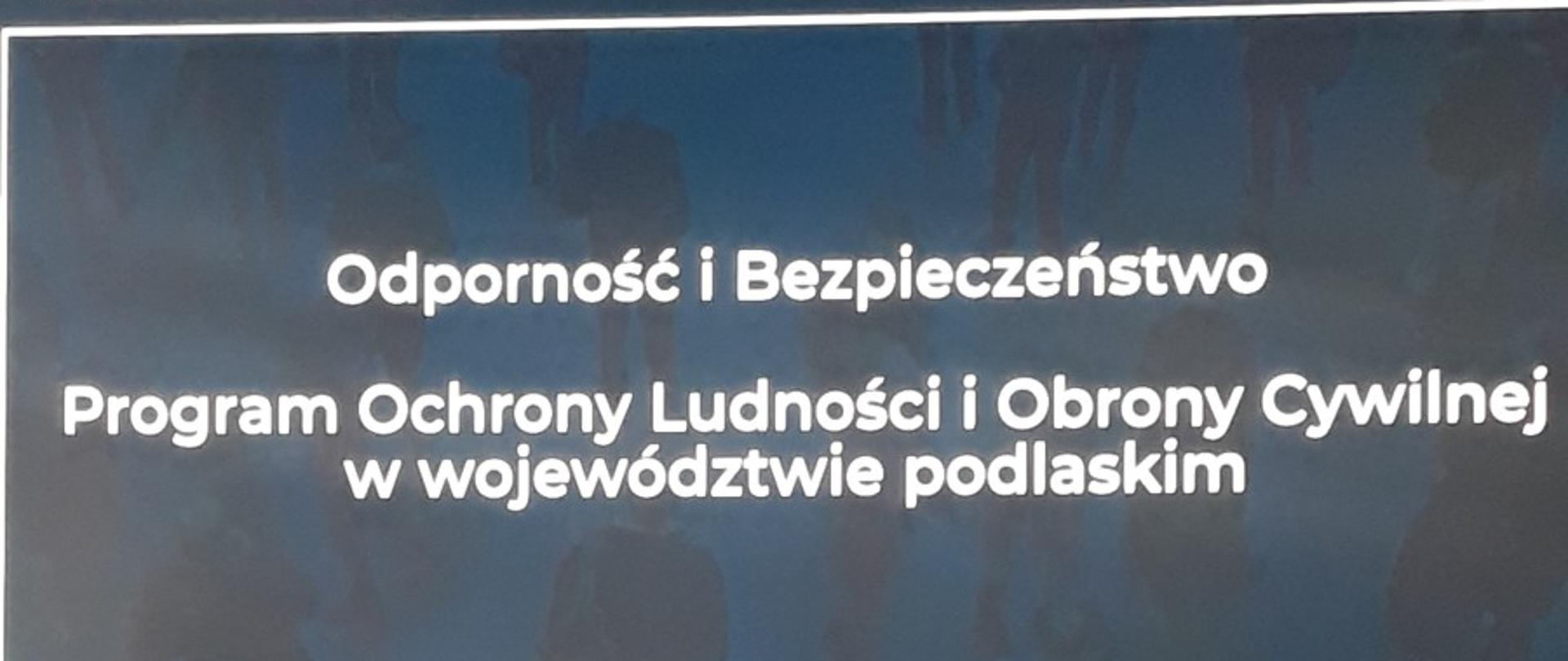 Mężczyzna prowadzi prezentację na scenie przed publicznością. 