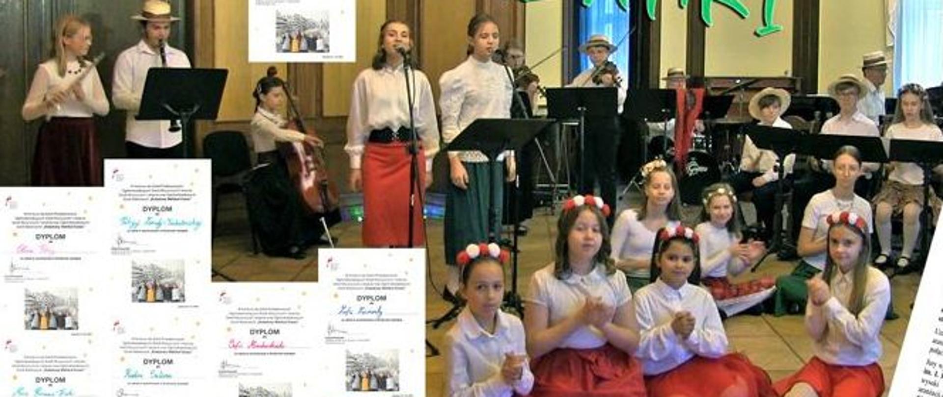 Zdjęcie kolorowe. W centralnej części grupa muzyków i wokalistów występujących w sali o klasycznym wystroju. W pierwszym planie cztery dziewczynki klęczące na podłodze, ubrane w białe bluzki, czerwone spódnice i opaski z kwiatami na głowach. Za nimi stoją dwie wokalistki w białych koszulach i długich spódnicach (czerwonej oraz ciemnej), śpiewające do mikrofonów. W tle po lewej stronie dziewczyna grająca na flecie oraz mężczyzna w kapeluszu grający na klarnecie. Obok nich dziewczyna grająca na wiolonczeli. Po prawej stronie widoczny zespół instrumentalny, w skład którego wchodzą osoby grające na skrzypcach, instrumentach klawiszowych oraz perkusji. Niektórzy muzycy mają na głowach słomkowe kapelusze. Nad grupą widnieje duży, zielony, stylizowany napis "MAZANKI!". Cała kompozycja jest otoczona licznymi miniaturami dyplomów rozmieszczonymi wzdłuż krawędzi obrazu. W prawym dolnym rogu umieszczono białą planszę z tekstem dotyczącym wydarzenia "KOLĘDOWY WEHIKUŁ CZASU III edycja".