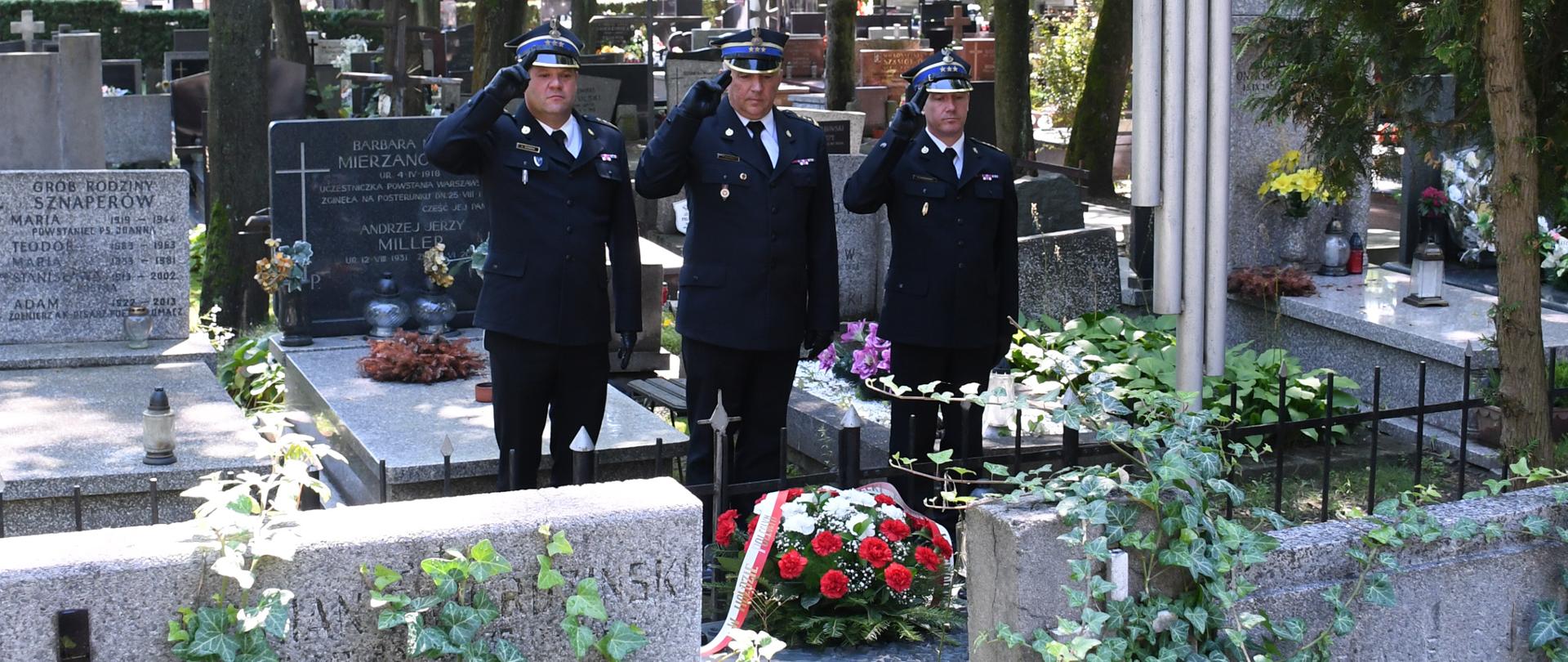 Komendanci i Naczelnik oddają honory przed mogiłą strażaków. 