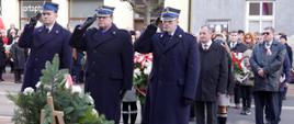 Widok z przodu. Delegacja strażaków KP PSP w Wadowicach salutuje po złożeniu wiązanki pod pomnikiem żołnierzy 12 Pułku Piechoty Wojska Polskiego. W tle pozostałe delegacje