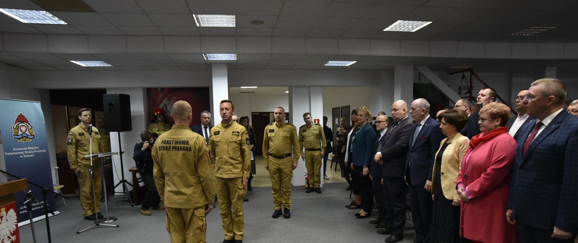 Zdjęcie wykonane w pomieszczeniu Komendy Miejskiej Państwowej Straży Pożarnej w Kaliszu. Na zdjęciu widać druhów OSP w umundurowaniu wyjściowym, funkcjonariuszy PSP w umundurowaniu wyjściowym oraz zaproszonych gości