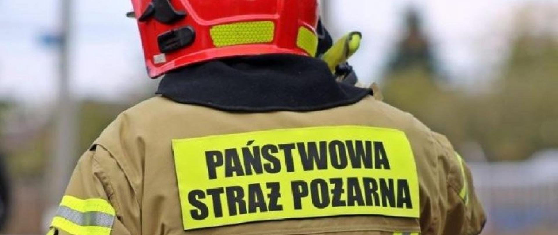 Strażak na zdjęciu, ma napis na plecach