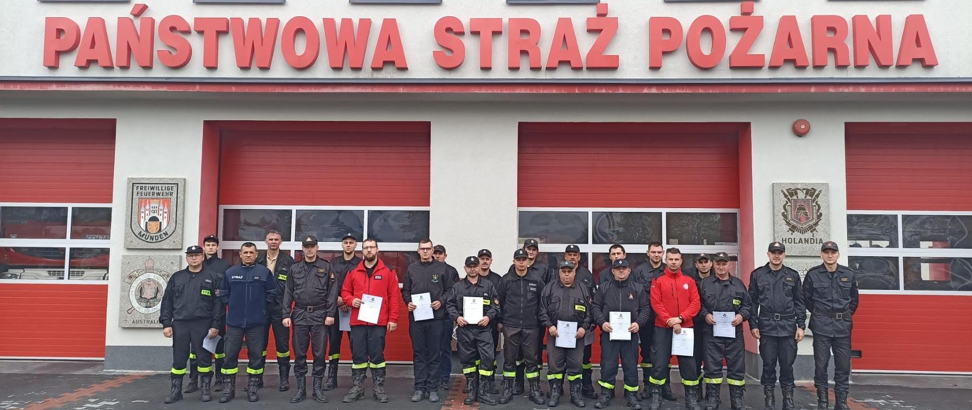 Szkolenie kierowców-konserwatorów sprzętu ratowniczego OSP - wspólne zdjęcie uczestników szkolenia przed budynkiem Komendy Powiatowej PSP w Chełmnie. 