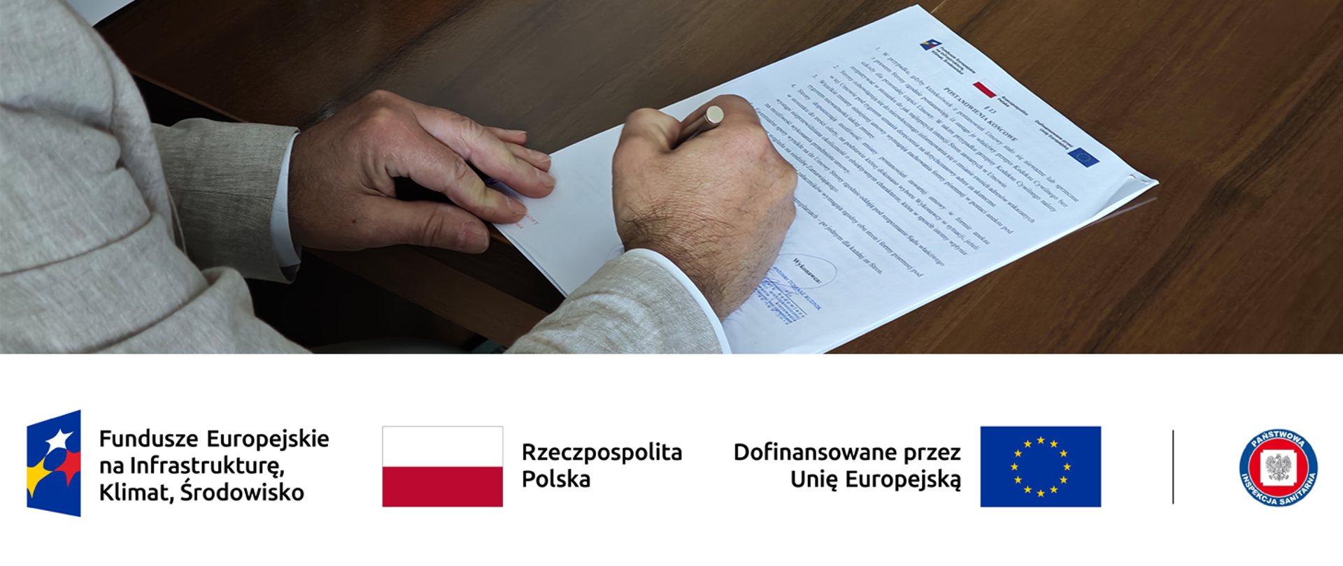 Podpisywanie dokumentów; poniżej logotypy Funduszy Europejskich, Polski i Unii Europejskiej a także Państwowej Inspekcji Sanitarnej