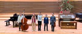 Dwóch chłopców i trzy dziewczynki stoją na scenie ze swoimi instrumentami.