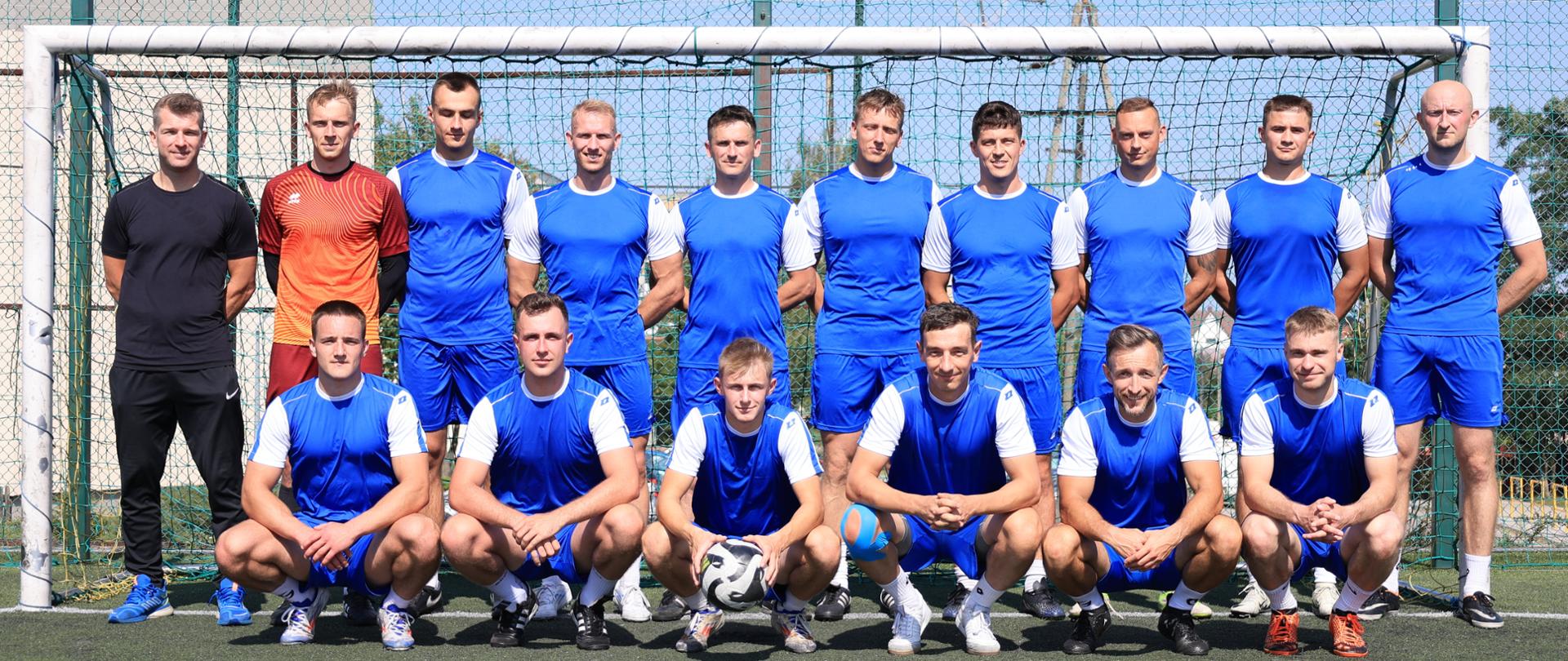 Podlascy strażacy przygotowują się do IV Mistrzostw Polski Strażaków w Piłce Nożnej 6-cio osobowej - cała drużyna - 18 zawodników pozuje na tle bramki piłkarskiej 