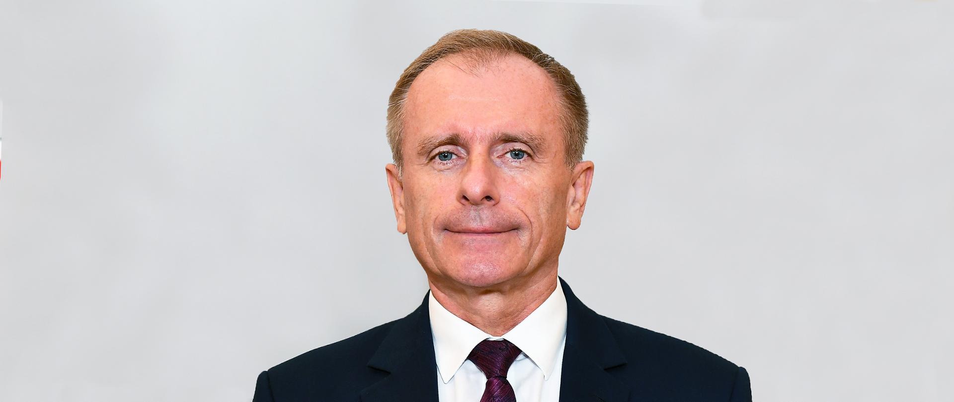 Na szarym tle członek Rady w garniturze 