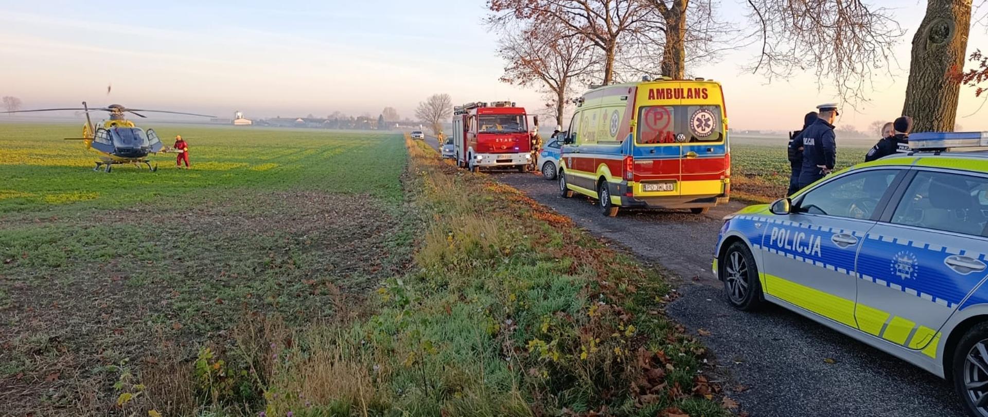 Na zdjęciu widać śmigłowiec Lotniczego Pogotowia Ratunkowego oraz pojazdy innych służb, które przybyły na miejsce zdarzenia.