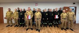 Strażacy stoją w świetlicy podczas przekazania wyróżnienia strażaka przez komendanta 