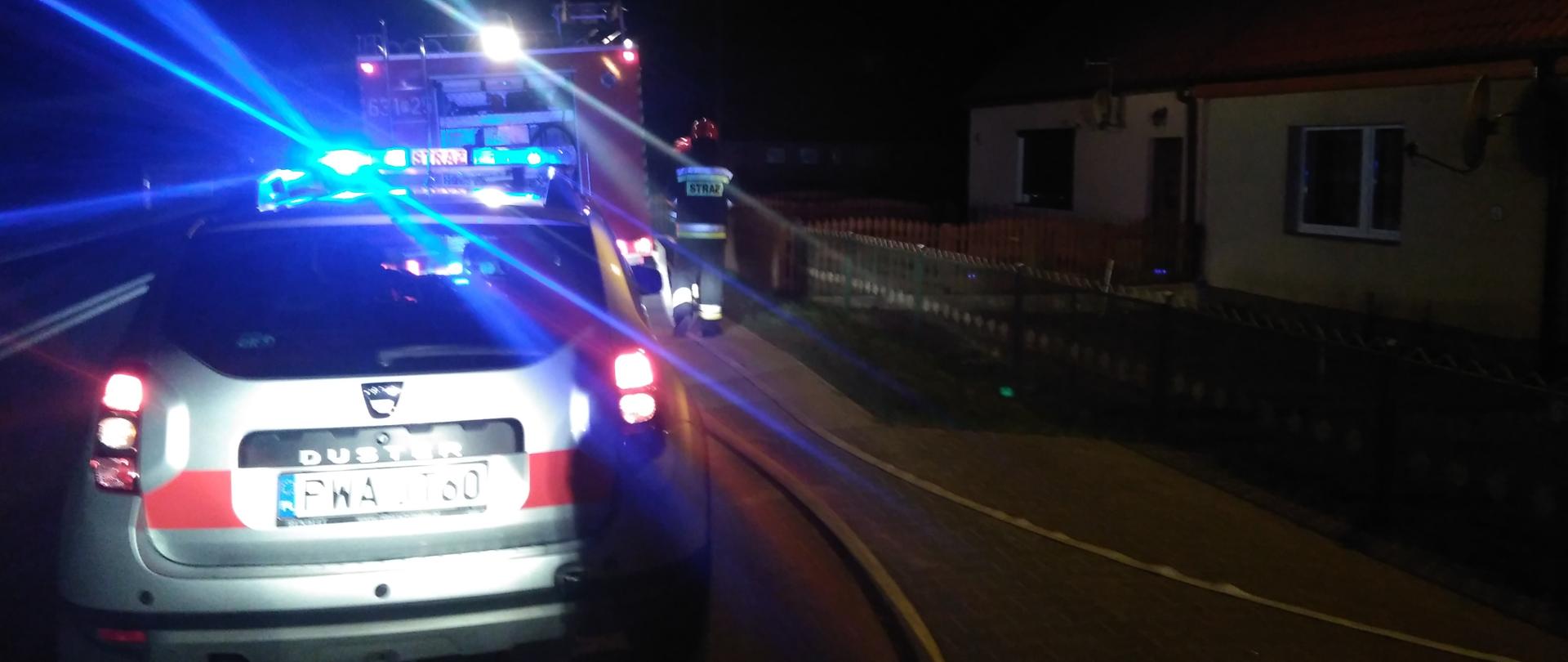 Na zdjęciu poglądowym widać dwa pojazdy straży pożarnej oraz strażaka nocą