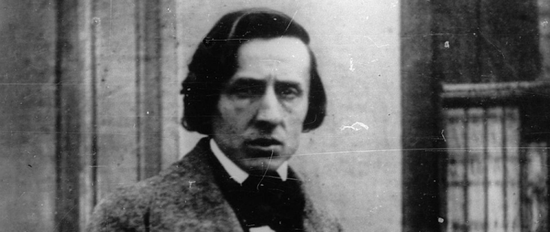 Czarno białe zdjęcie Fryderyka Chopina, na tle budynku