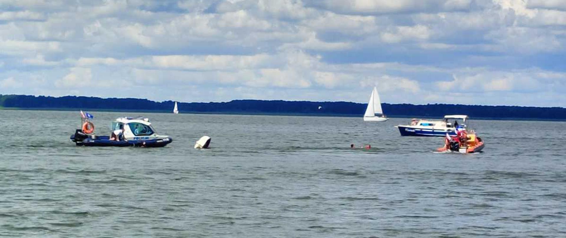 Łódź z PSP i Policji podejmuje osoby poszkodowane z wody. 