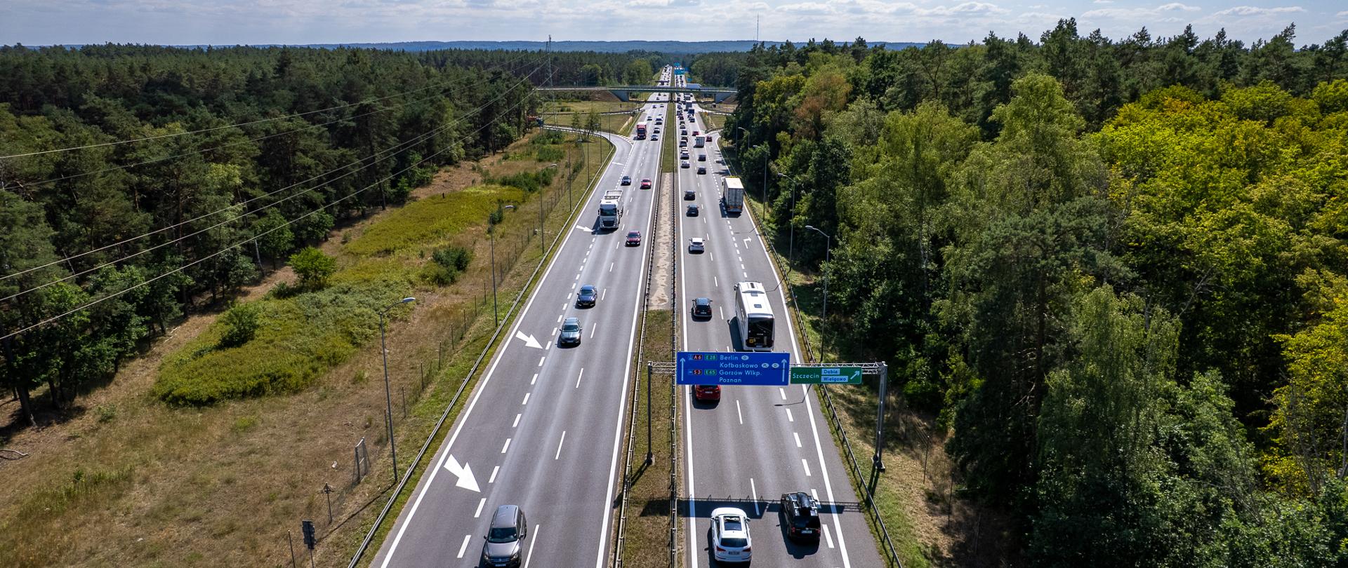 Droga w terenie leśnym z ruchem pojazdów i oznakowaniem