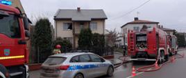 Na zdjęciu samochód gaśniczy OSP KSRG w Grajewie, radiowóz policyjny oraz samochody gaśnicze PSP w Grajewie. W tle budynki mieszkalne jednorodzinne.