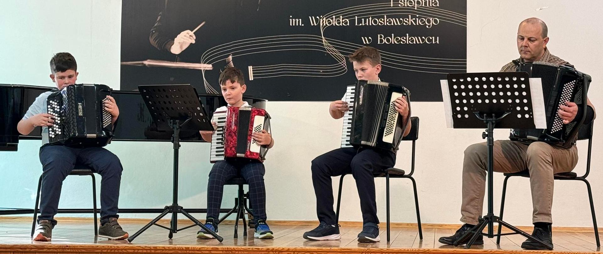 Zdjęcie przedstawiające wykonawców - kwartet akordeonowy, podczas koncertu klasy akordeonu pana Bogusława Kłaka, który odbył się 8 kwietnia 2024 r. w auli szkoły.
