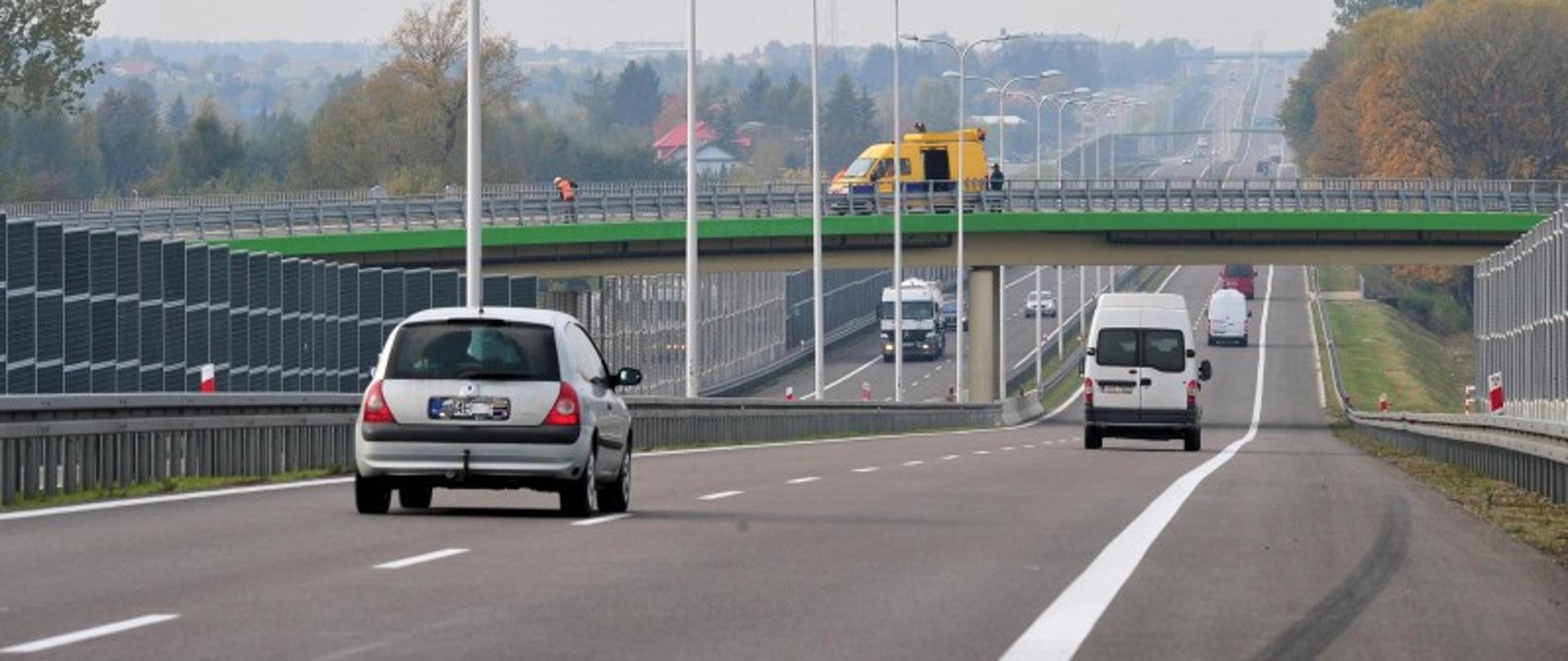 Zdjęcie przedstawia drogę szybkiego ruchu. Po obu stronach jezdni widoczne ekrany akustyczne.