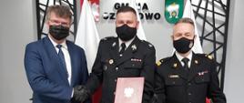 Wiceminister Maciej Wąsik ściska dłoń prezesa OSP Bratniki Krzysztofa Sobczyka. Obok stoi Komendant Główny PSP