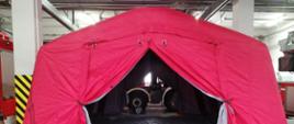 Czerwony namiot pneumatyczny stojący na szarej posadzce garażu