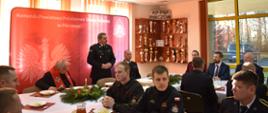 Zdjęcie przedstawia Komendanta Powiatowego składającego świąteczne życzenia osobą obecnym na świątecznym spotkaniu.