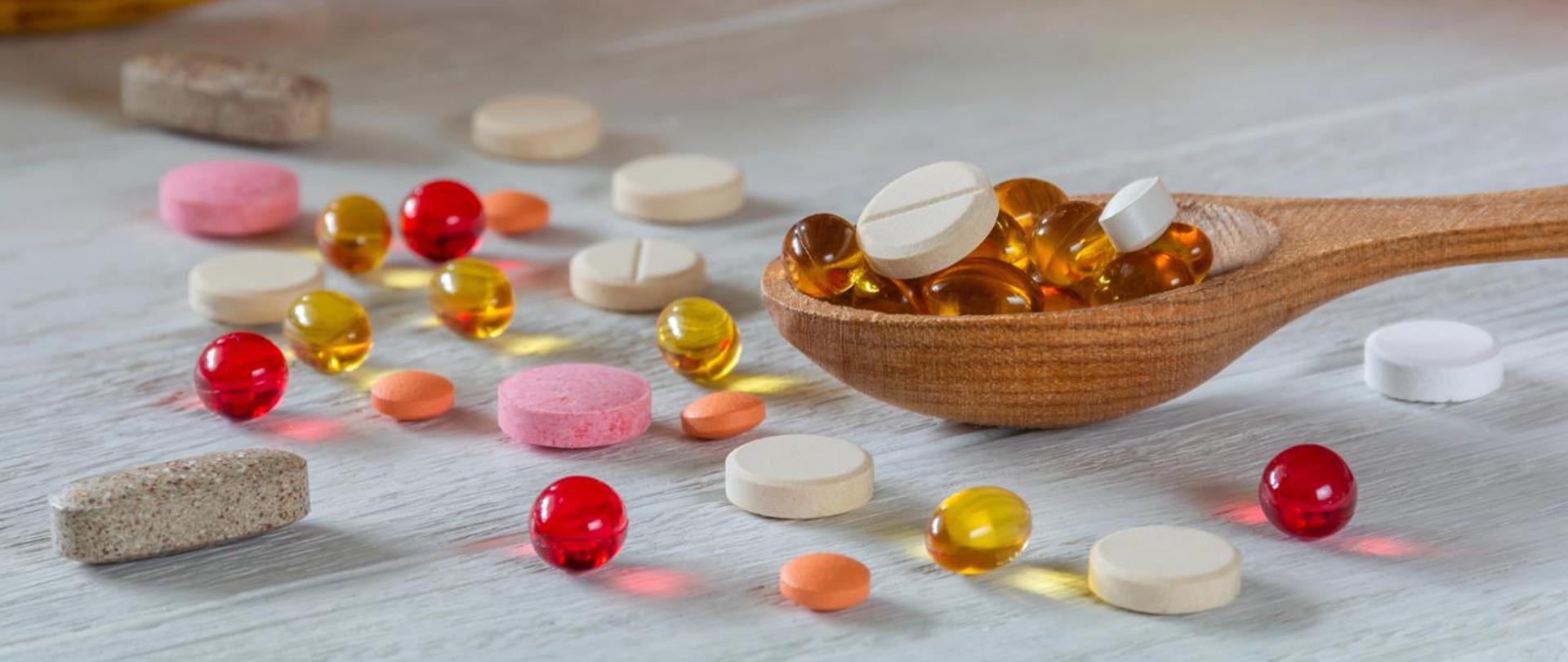 kolorowe tabletki w formie kapsułek i tabletek. Łyżka drewniana