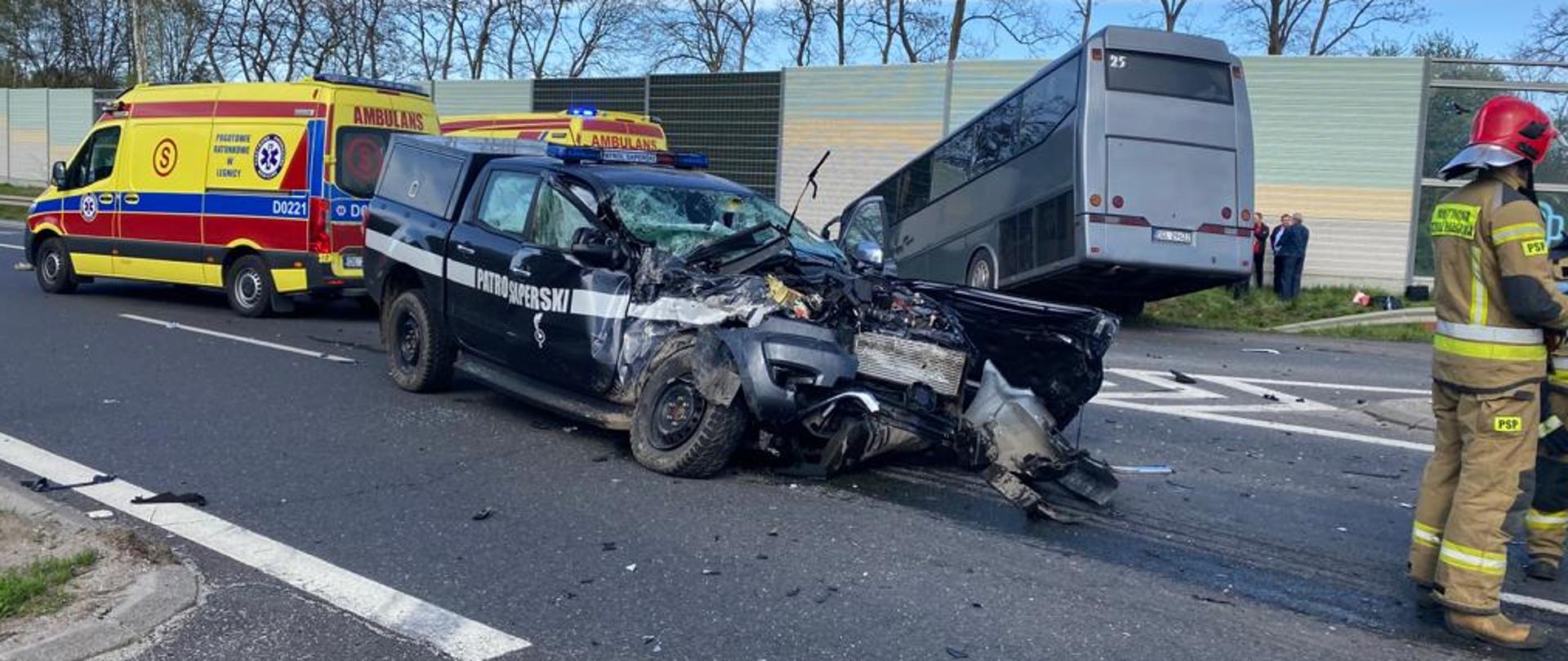Pojazd wojskowy patrolu saperskiego na tle karetek pogotowia oraz autobusu