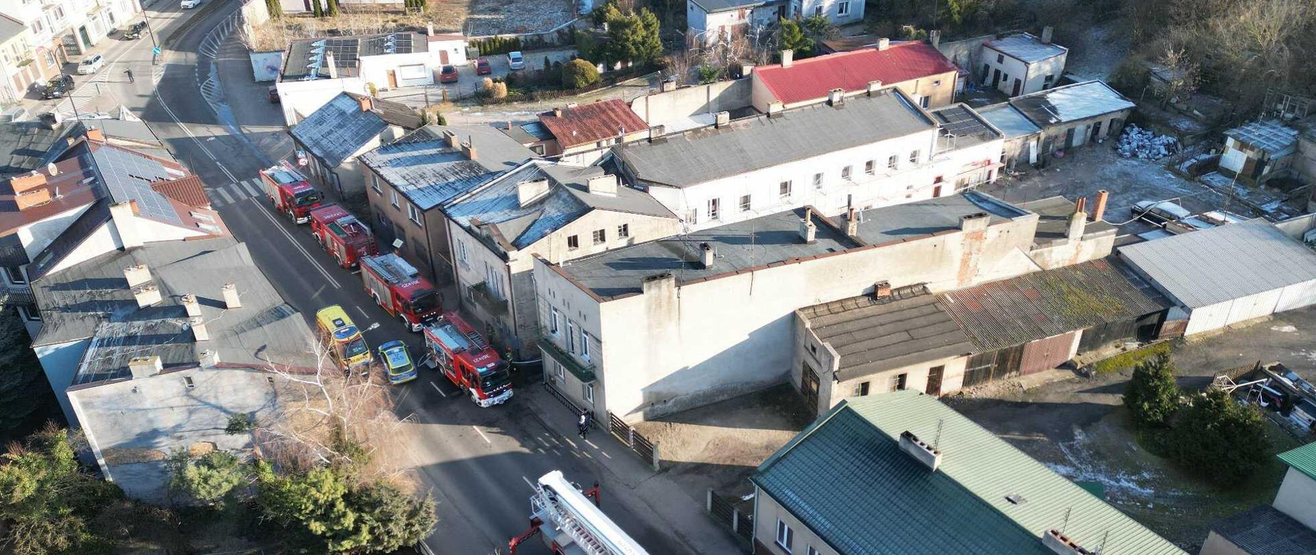 Zdjęcie z lotu ptaka. Na ulicy zaparkowane samochody strażackie, policja oraz pogotowie ratunkowe. 