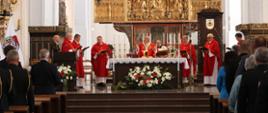 Kapłani odprawiają mszę stojąc za ołtarzem w ławkach siedzą przedstawiciele służb mundurowych oraz zaproszeni goście.