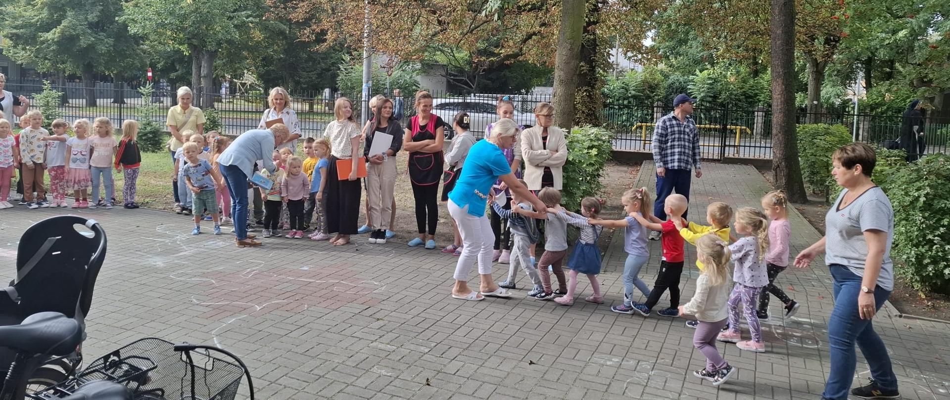 dzieci i opiekunowie podczas zbiórki podczas próbnej ewakuacji