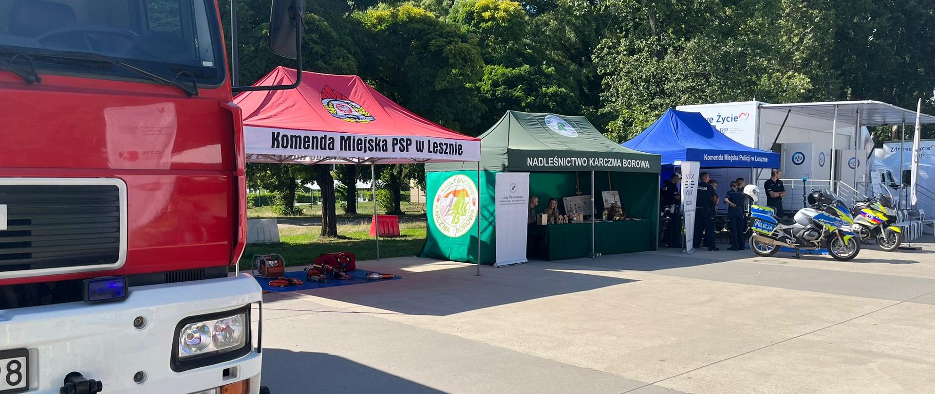 Namioty rozstawione po obu stronach ulicy, motor stoi na drodze.