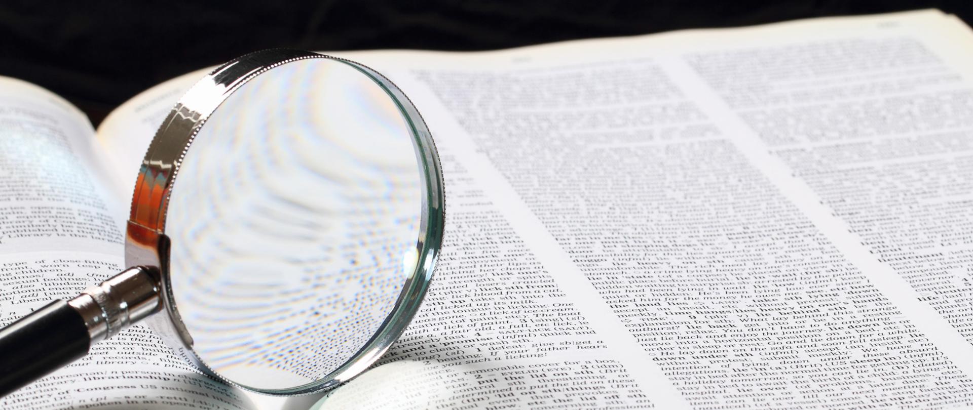 Dictionary with an magnifying glass on top