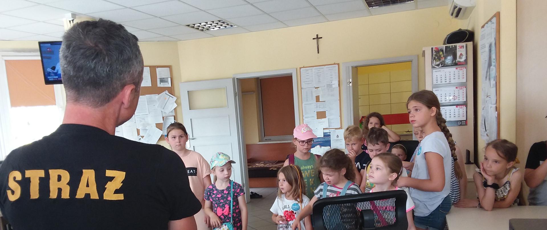 Strażak omawia i pokazuje dzieciom sprzęt pożarniczy