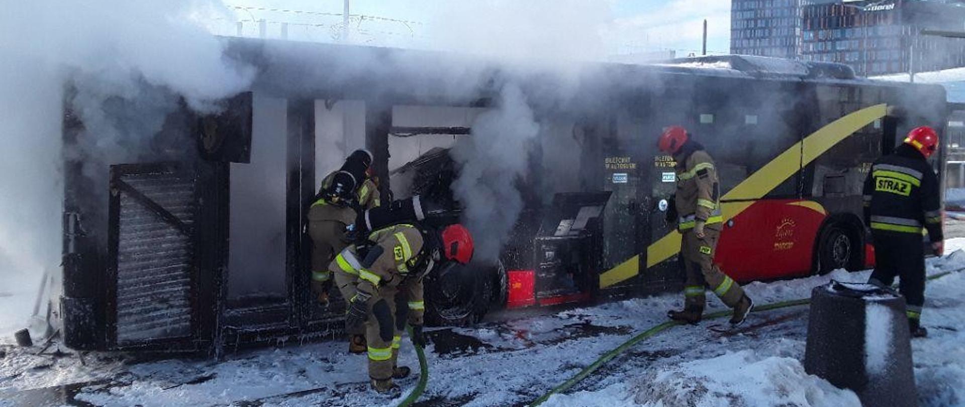 Strażacy prowadzący działania gaśnicze w palącym się autobusie