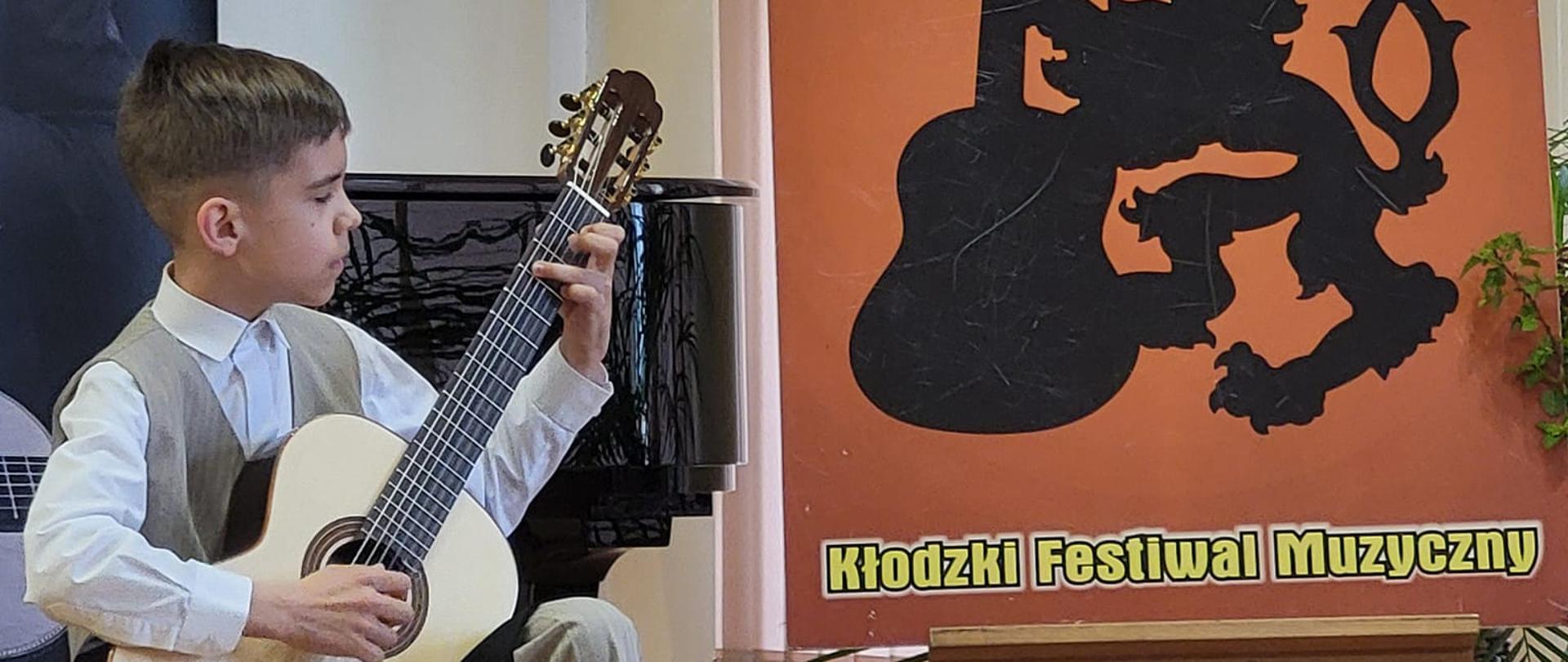 Uczeń Emilian Klimonda gra na gitarze na scenie auli PSM Klodzko podczas występu na XXV konkursie GITARIADA 