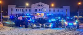 przed jednostką policjij stoją samochody straży pożarnej i policji z sygnałami świetlnymi oraz strażacy i policjanci na baczność, wieczór, oddanie hołdu poległym policjantom