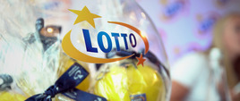 Szklany pojemnik z logo LOTTO oraz żółtymi kulami z numerami