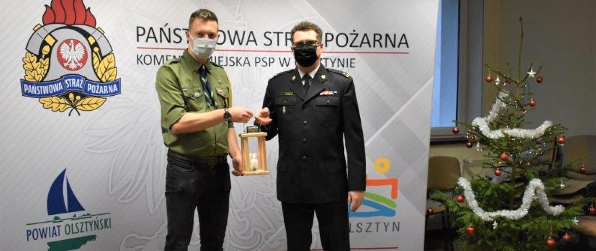 Zdjęcie przedstawia Komendanta Chorągwi Warmińsko-Mazurskiej ZHP hm. Macieja Micielskiego przekazującego lampion z Betlejemskim Światłem Pokoju Komendantowi Miejskiemu PSP w Olsztynie mł. bryg. Jarosławowi Gryciukowi 