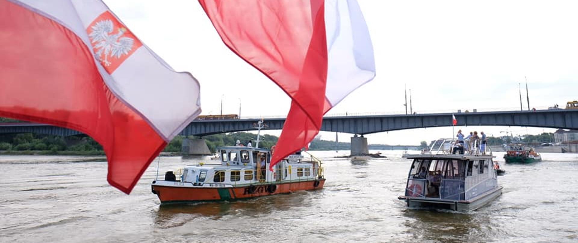 barki płynące po Wiśle w stronę kanału Żerańskiego, na pierwszym planie flaga Polski.