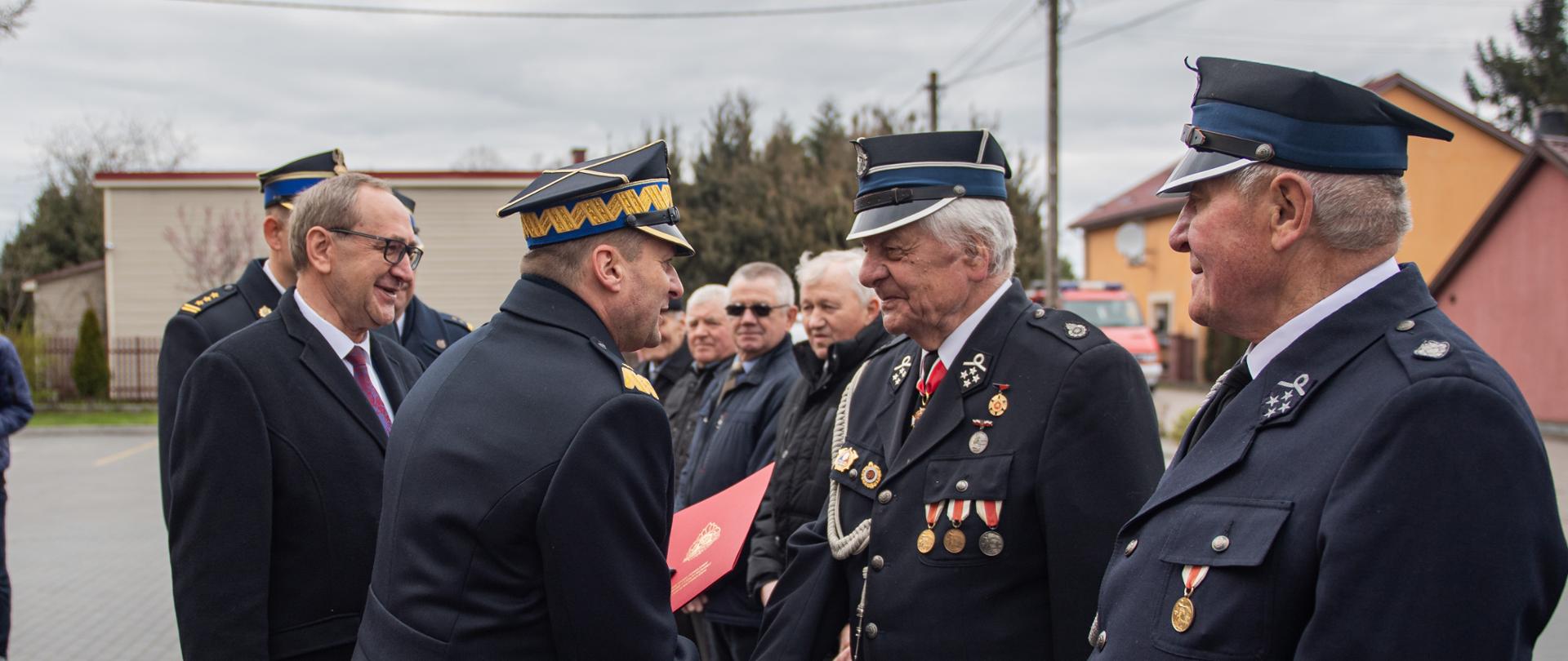 Zastępca komendanta głównego PSP w trakcie wręczania wyróżnień druhom OSP ustawionym w szeregu. 