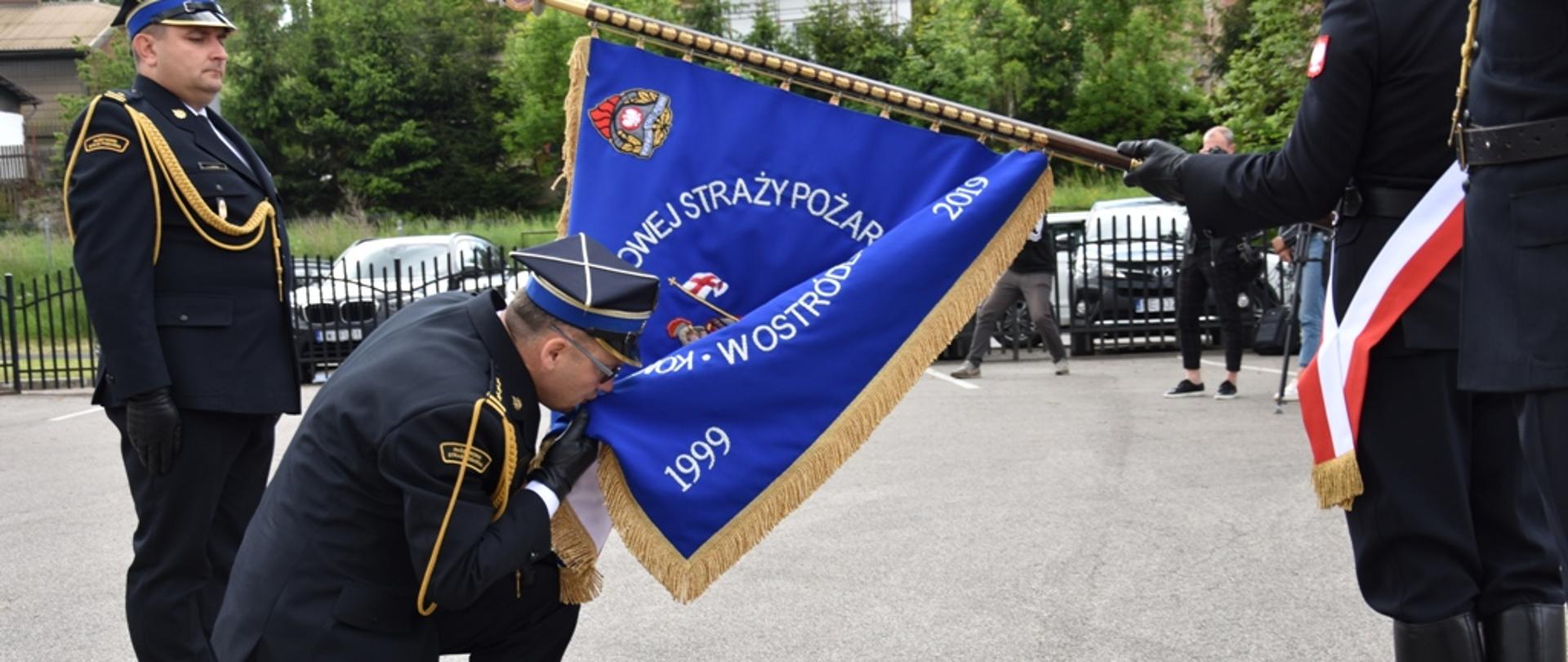 Komendant Ostrowski całuje płat sztandaru. 