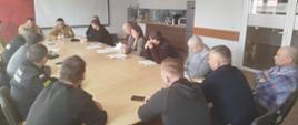 Przedstawiciele jednostek OSP oraz przedstawiciele samorządów gminnych podczas spotkania z kierownictwem Komendy Powiatowej PSP w Lwówku Śląskim siedzący wspólnie przy stole.