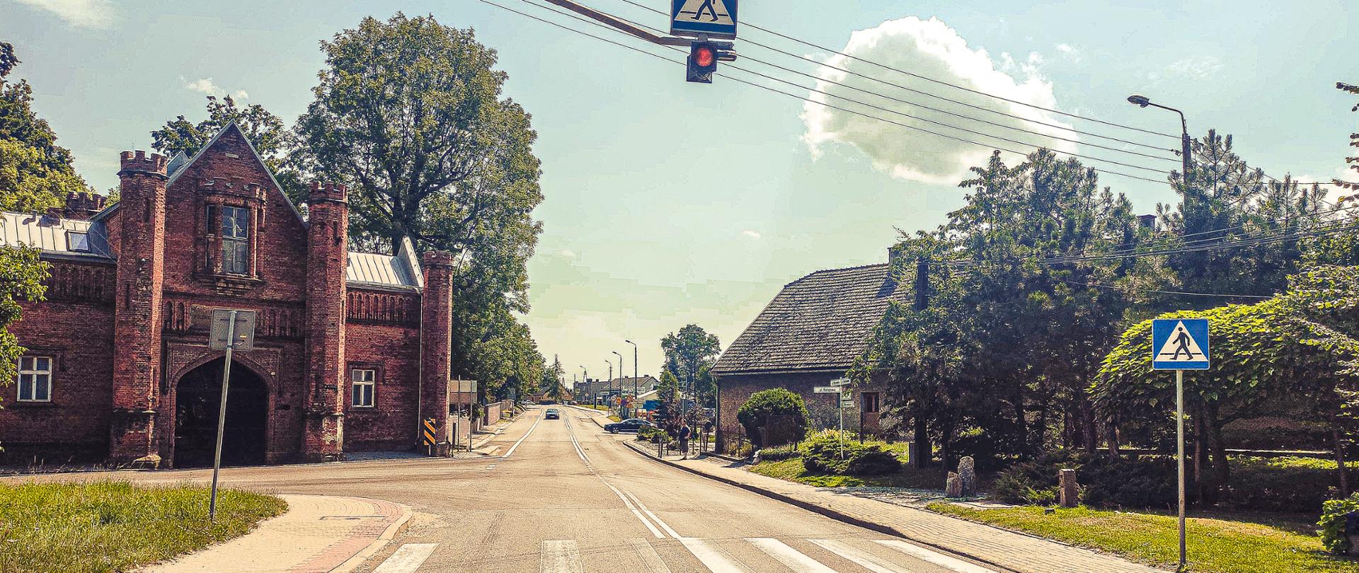 Przejście dla pieszych w ciągu DK45 w Krzyżownicach, wyposażone w podświetlony i wyniesiony nad przejście dla pieszych znak D6 „przejście dla pieszych” wraz z pulsującą sygnalizacją ostrzegawczą w kolorze żółtym. 